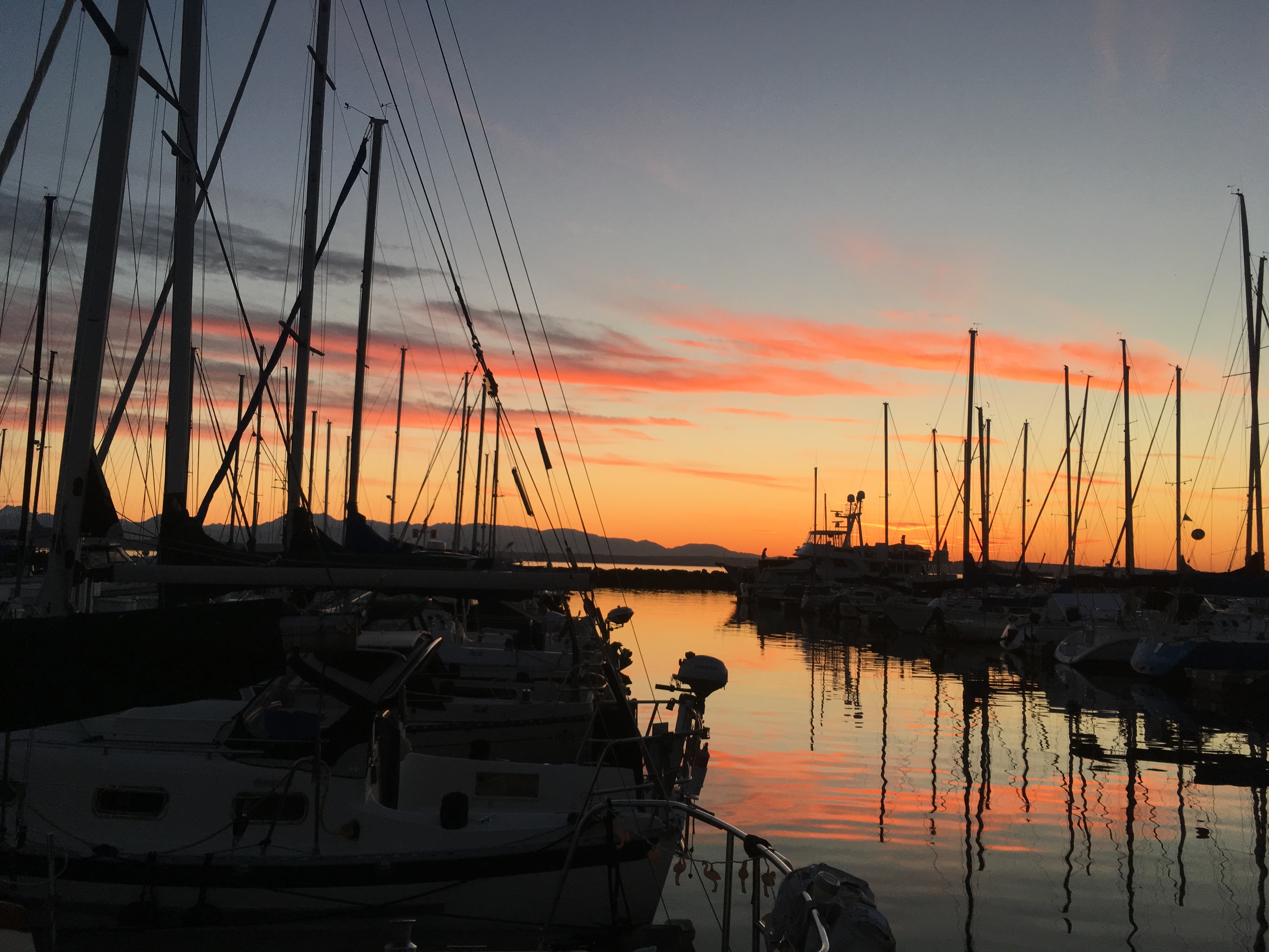 Marina slips glowing under a vivid sunset sky.